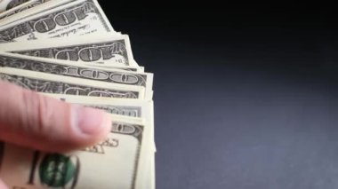 Siyah arka plandaki 100 dolarlık banknotları sayarak erkek ellerine yaklaş. Bir adam bir sürü Amerikan doları gösterir. 4K Video