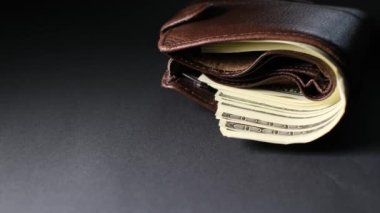 Kahverengi, hakiki deri cüzdanın üst görüntüsü içinde banknotlar ve kredi kartı, siyah arka planda izole edilmiş..