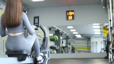Seksi bir kadın spor salonunda modern bir simülatörde spor yapıyor. Fitness yaşam tarzı konsepti.