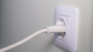 Tehlikeli cihazları prizden ayırıyorum. Bir kadının eli elektrik prizinin elektriğini kesiyor. Yavaş çekim