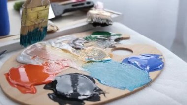 Palette kalın bir fırça ile karıştırılmış akrilik boya. Bir resim yaratma süreci. Renk paletini kapat