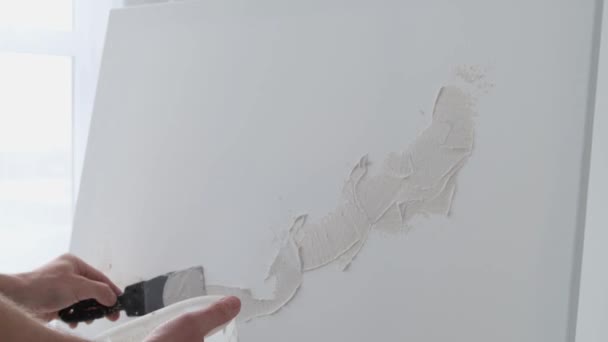 一位年轻的画家在洁白的画布上涂上了白漆 白色调的艺术工作室 开始画一幅画 — 图库视频影像