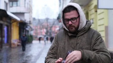 Genç bir adam hasta, o yağmurda sokakta hapşırır. Sağlıksız bir adam şehirde yürüyor ve öksürüyor ve hapşırıyor. Grip salgını. 4k video
