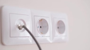 Connecting the electrical appliance to the outlet 100-127 volts 60 hertz. Close-up of a womans hand inserting a plug into an electrical outlet