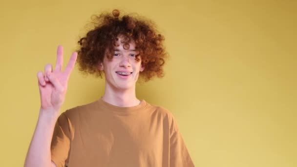 Smiling American Student Yellow Background Studio Shows Victory Gesture His — Stock Video