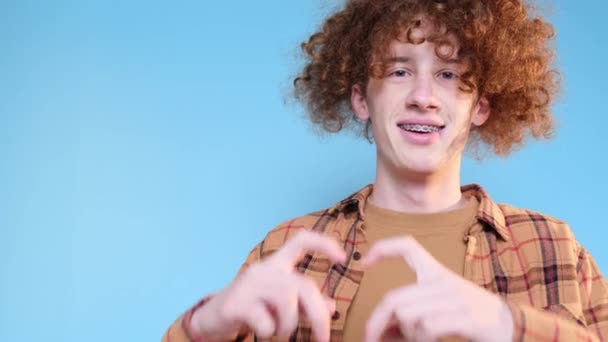 Curly Handsome Man Makes Heart Gesture Blue Background Valentines Day — Vídeo de Stock