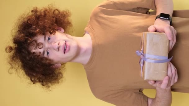 Young Curly Handsome Man Holding Gift Wrapped Yellow Paper Young — Video