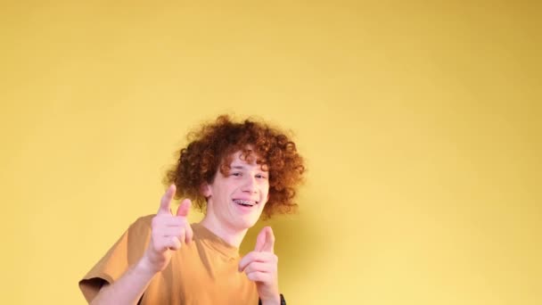 在演播室里 一个时髦而快乐的卷曲少年男孩被隔离在黄色的背景下 一个年轻人的快乐的情绪 幸福的概念 — 图库视频影像