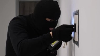 A robber in a black mask opens the safe and steals money. Apartment thief. Hacking the safe. 4k video