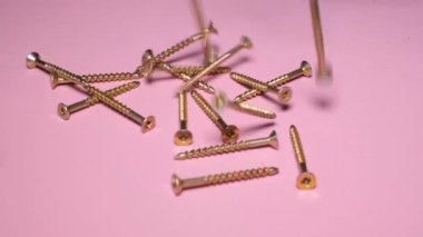 Self-tapping screws for metal on a pink background. Macro video of Phillips head carpentry screws. Concept of building materials. Place for advertising