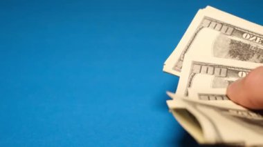 Close-up of a mans hand counting dollars on a blue background. Background for business advertising.