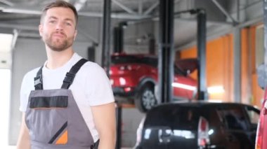 Close-up of a car mechanic holding a key, he crossed his arms and looks at the camera. Professional car repair in Australia