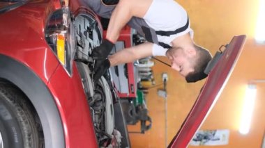 A mechanic examines a cars engine. The concept of car repair in the USA. Vertical video