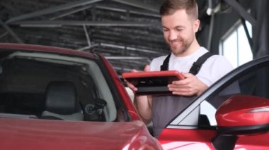 Computer diagnostics of the correct operation of the electric vehicle. Car mechanic with a tablet in his hands. 4k video