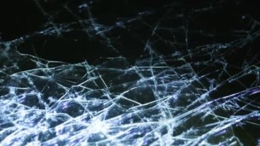 Broken glass with many cracks illuminated by light. Background from broken glass. Video macro shooting