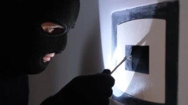 A robber in a black mask opens the safe and steals money. Apartment thief. Hacking the safe. 4k video