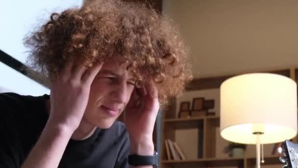 ソファに座って頭を抱えている若い男の片頭痛と片頭痛 疲労とうつ病 — ストック動画