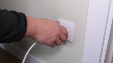 Close-up of a mans hand turning off electrical appliances from an electrical outlet. Energy saving. 4k video