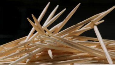 A pile of wooden toothpicks on a black background. Macro. Texture. Movement in a circle