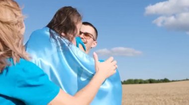 Happy Ukrainian family in wheat field with blue and yellow flag of Ukraine. Ukraines victory in the war. Independence Day of Ukraine