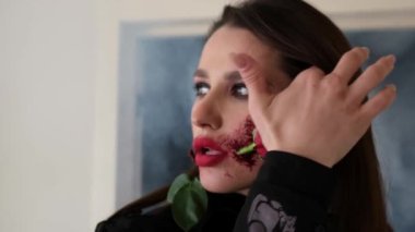 A girl with a beautiful artistic make-up with a rose in her mouth. Unusual make-up on the face.
