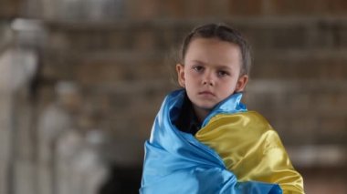 Portrait of a sad child with a Ukrainian flag. Migrant children from Ukraine. Russias aggression against Ukraine