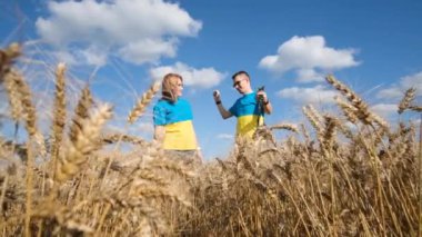 A family in t-shirts with the Ukrainian flag sings in the middle of a wheat field. Independence Day of Ukraine.