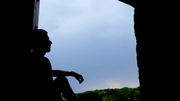 一个人在深蓝色天空的背景下歌唱的轮廓 一个靠近一个大窗户的男人 框架中的乌云 — 图库视频影像