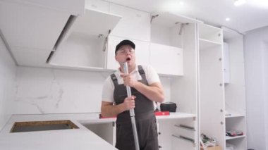 Young cheerful caucasian funny man listening to song and singing and dancing while renovating house. Modern home renovation. High quality 4k video
