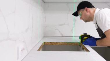 The master installs furniture in the kitchen room using a high-precision construction laser. The concept of home renovation