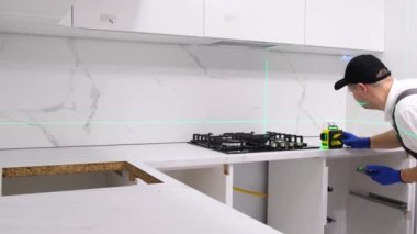 A service technician installs a gas stove in the kitchen using an electronic laser. High quality 4k video