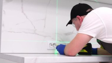 A master electrician installs a 220 volt socket, he uses a screwdriver and a level laser. Professional electrician