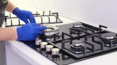A repairman repairs a gas stove close-up. Repair of appliances in the kitchen room. 4k video