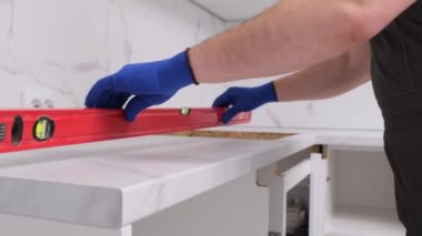 A furniture worker with a level and a ruler measuring the horizontal surface of a white cabinet. High quality 4k video