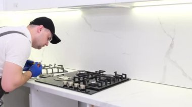 A gas engineer repairs a gas stove in the kitchen. The call of the master gas fitter to the house. 4k video