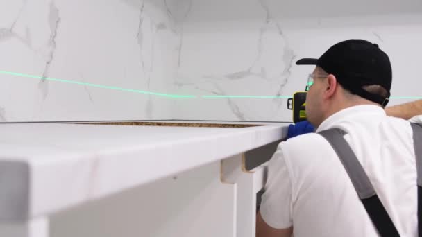 Мастер Устанавливает Мебель Кухонном Помещении Помощью Высокоточного Строительного Лазера Концепция — стоковое видео