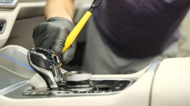 Washing the car interior with a soft brush and foam. A car service worker wipes the instrument panel with a special brush.