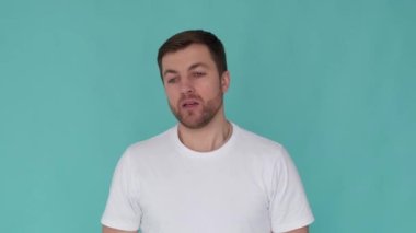 Handsome blond american appearance talking to the camera. Interview on a blue background. The guy in the white T-shirt. Accelerated video