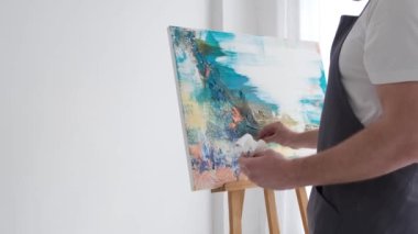 Work on creating an abstract painting in the studio in white. A young artist paints a picture in blue