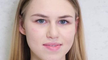 Young blonde woman smiling on a gray background in the studio. Close-up portrait of happy girl, fashion model smile. 4k video