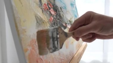 The hand of a talented artist paints an abstract painting with a brush. Implement your great ideas on canvas