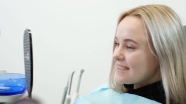 A satisfied patient looks at the healed teeth in the dental mirror. The result of dental treatment. A healthy oral cavity