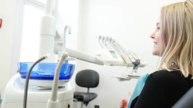 Young smiling blonde in dental chair showing thumb up. Satisfied patient. Timely treatment of teeth
