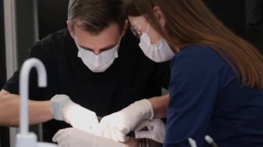 Dental treatment process. The dentist holds the tools in his hands and examines the teeth with the help of an assistant. A patient at the dentist. Dental office.