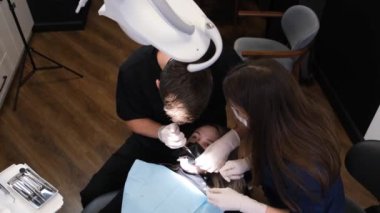 Dental treatment process. Male dentist and assistant treat teeth using modern methods. Painless treatment of the oral cavity