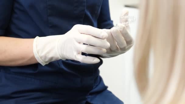歯医者の診察 手袋の歯科医は プラスチック歯のサンプルを保持しています プラスチック歯のモデル — ストック動画
