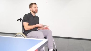 Attractive young man playing ping pong while sitting in a wheelchair. The life of people with disabilities is not a sentence