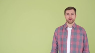 Attractive young actor, student, presenter makes a presentation on an olive background. I present with the help of hand gestures. Points at someone