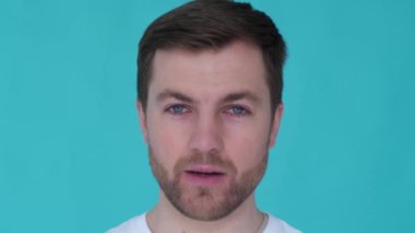 Head of an attractive guy close up on a blue background. Conceived actor. Sign language. Beautiful eyes