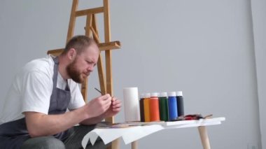 Conceived focused young artist is preparing to create a modern masterpiece. The talented artist works in the studio. The artist thinks and looks out the window